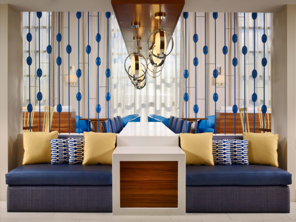 A modern hotel lobby featuring blue and yellow accents, showcasing contemporary furniture and stylish decor.
