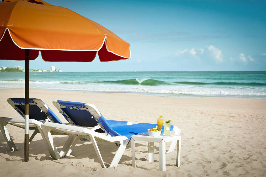 A beach umbrella with two chairs set up on the sandy shore, creating a relaxing seaside atmosphere.