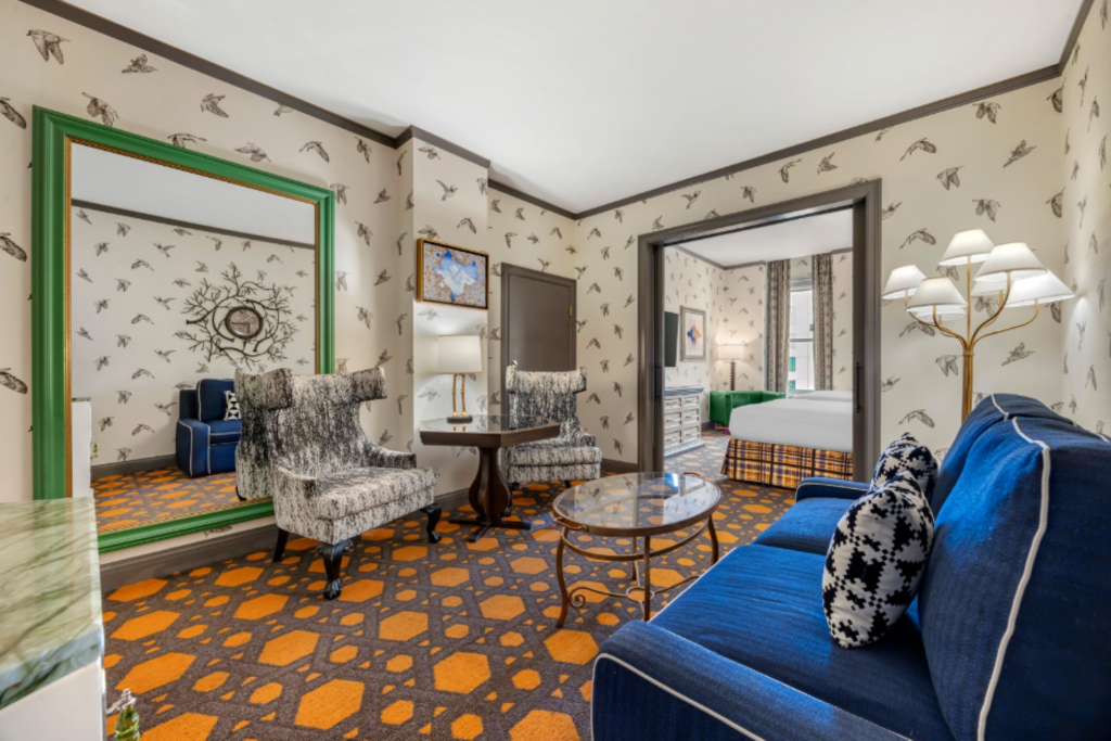 A cozy suite showcasing a blue couch, a coordinating chair, and a mirror enhancing the space.