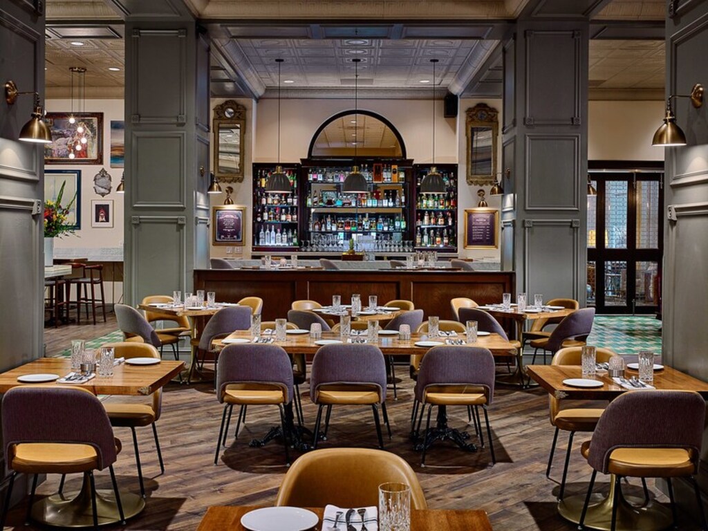 A view of the hotel restaurant featuring a bar area and several dining tables arranged for guests.